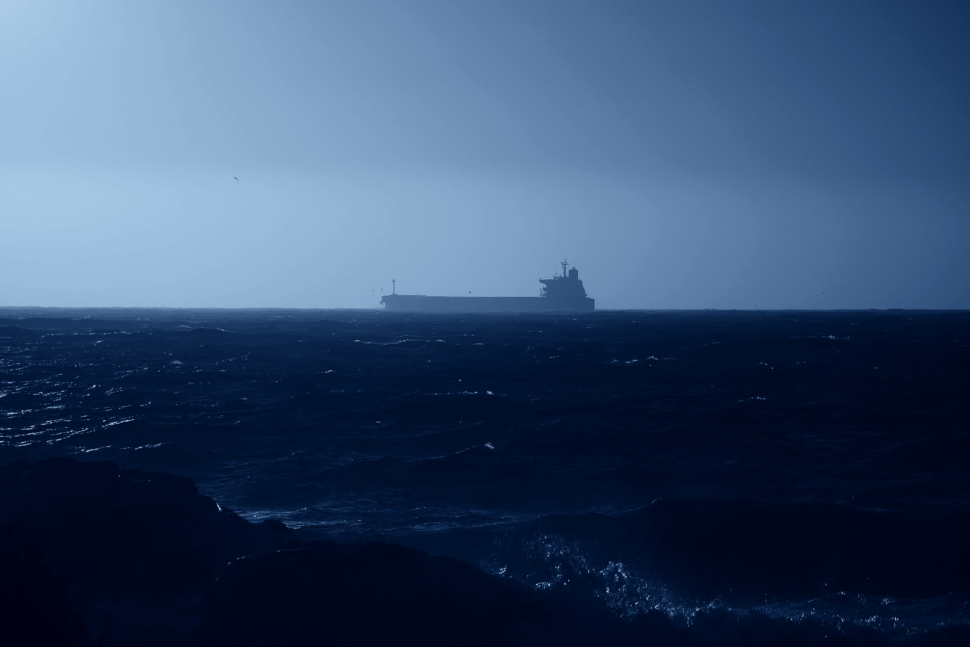 Cargo ship silhouette on a dark blue sea